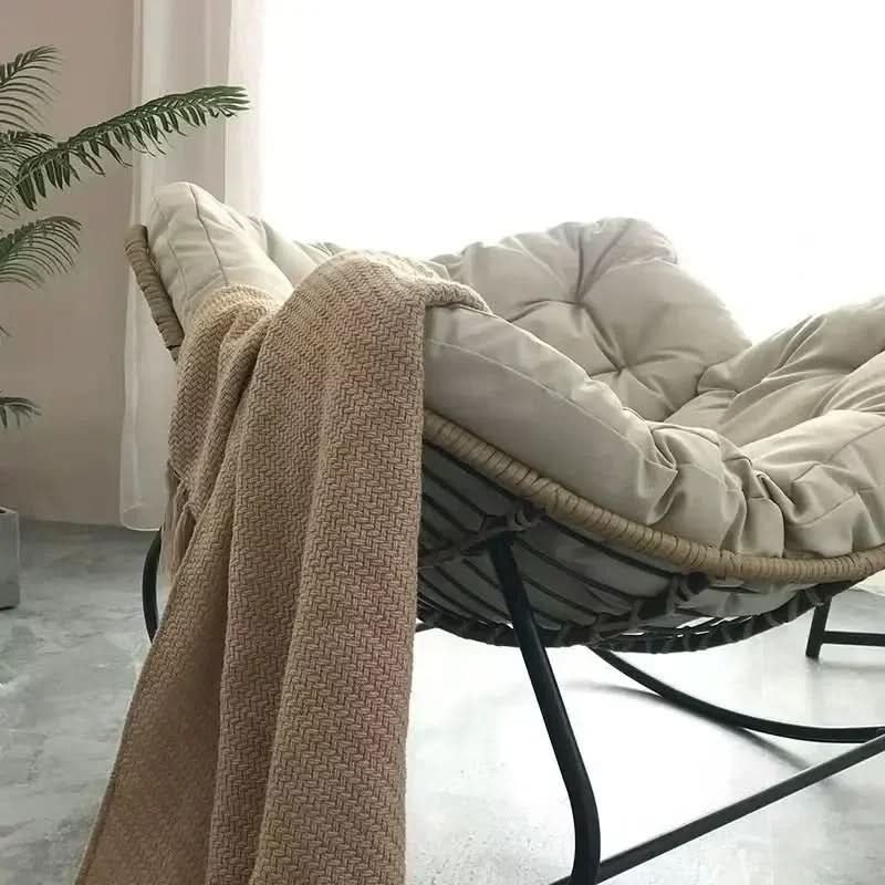 bild på en vit, bekväm stol i en avslappnad miljö, med en filt hängande på den